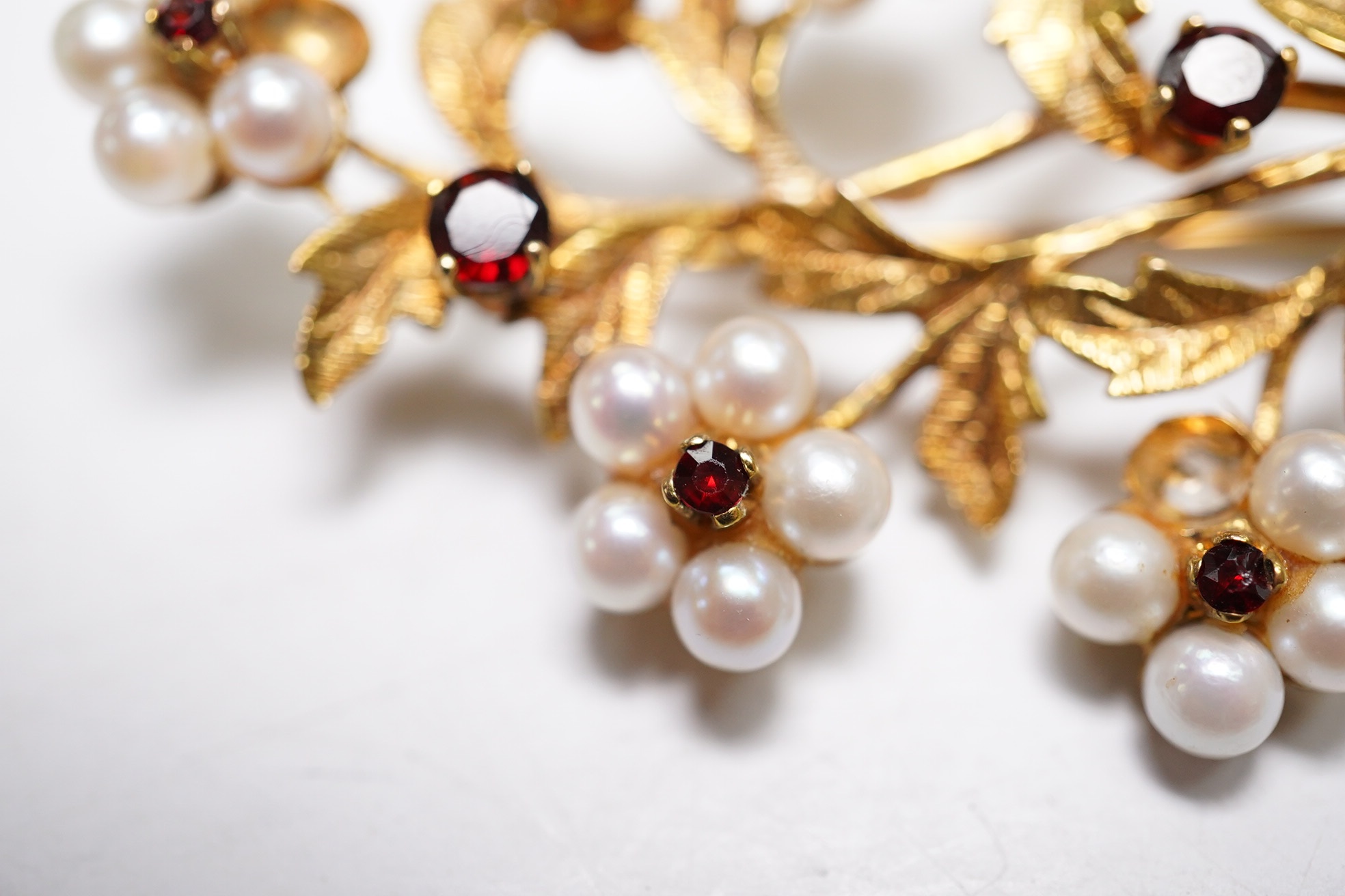 A 1960's 9ct gold, cultured pearl and garnet cluster set foliate spray brooch, 52mm (three pearls missing), gross weight 9.3 grams. Condition - poor